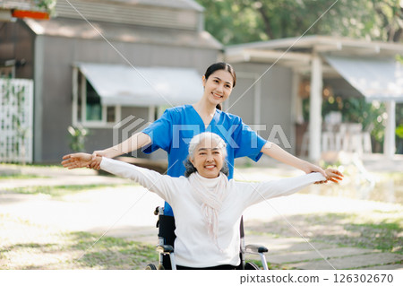 Elderly asian senior woman on wheelchair with Asian careful caregiver and encourage patient, walking in garden. with care from a caregiver Elderly asian senior woman on wheelchair with Asian careful caregiver and encourage patient, walking in garden. with care from a caregiver 126302670