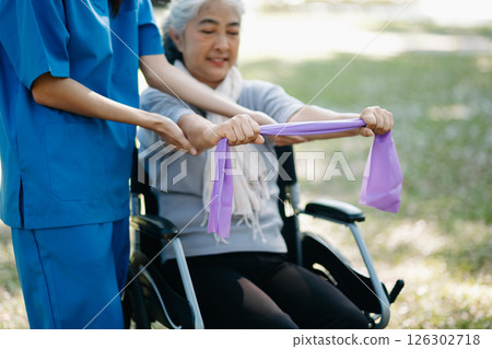 Asian physiotherapist helping elderly woman patient stretching arm during exercise correct with dumbbell in hand during training hand with patient Back problems in the garden. 126302718