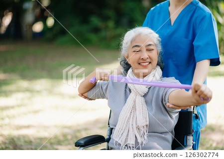 Asian physiotherapist helping elderly woman patient stretching arm during exercise correct with dumbbell in hand during training hand with patient Back problems in the garden. Asian physiotherapist helping elderly woman patient stretching arm during exercise correct with dumbbell in hand during training hand with patient Back problems in the garden. 126302774