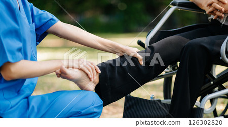 Asian physiotherapist helping elderly woman patient stretching arm during exercise correct with dumbbell in hand during training hand with patient Back problems in the garden. 126302820