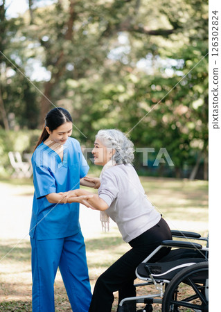 Asian young caregiver nurse support senior older female walking outdoors. Specialis doctor help and take care of elderly mature. Asian young caregiver nurse support senior older female walking outdoors. Specialis doctor help and take care of elderly mature. 126302824