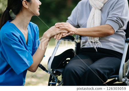 Elderly asian senior woman on wheelchair with Asian careful caregiver and encourage patient, walking in garden. with care from a caregiver and senior health insurance. 126303059