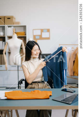 Asian tailor woman working on clothes in tailoring atelier. beautiful young female fashion designer smile and after success in studio Asian tailor woman working on clothes in tailoring atelier. beautiful young female fashion designer smile and after success in studio 126303256