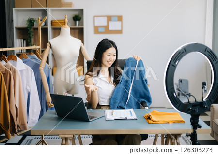 Fashion blogger concept, Young women selling clothes on video streaming.Startup small business SME, using smartphone or tablet taking receive and checking 126303273