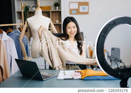 Fashion blogger concept, Young women selling clothes on video streaming.Startup small business SME, using smartphone or tablet taking receive and checking 126303276