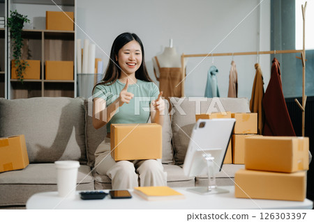Asian lady blogger showing clothes in front of the camera to recording vlog video live streaming 126303397