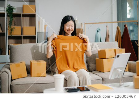 Asian lady blogger showing clothes in front of the camera to recording vlog video live streaming Asian lady blogger showing clothes in front of the camera to recording vlog video live streaming 126303467