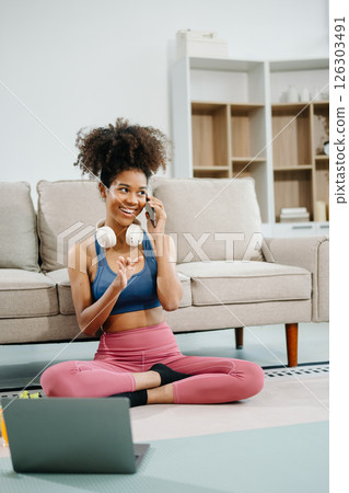 Active woman in athleisure sitting on yoga mat with tablet, headphones and modern home lifestyle. Active woman in athleisure sitting on yoga mat with tablet, headphones and modern home lifestyle. 126303491