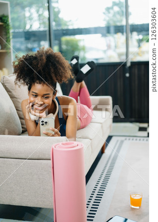 Active woman in athleisure sitting on yoga mat with tablet, headphones and modern home lifestyle. 126303604