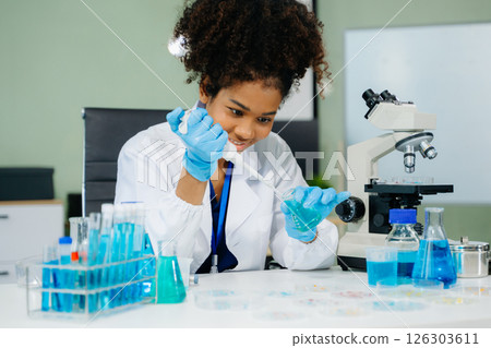 Young scientists conducting research investigations in a medical laboratory, a researcher in the foreground Young scientists conducting research investigations in a medical laboratory, a researcher in the foreground 126303611