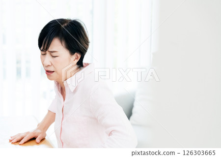 Middle-aged woman suffering from back pain in the living room 126303665