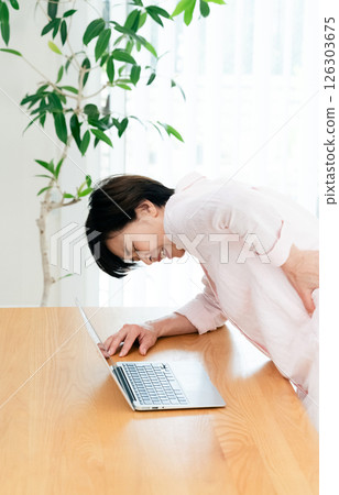 Middle-aged woman suffering from back pain in the living room Middle-aged woman suffering from back pain in the living room 126303675