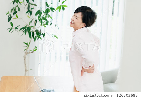 Middle-aged woman suffering from back pain in the living room 126303683
