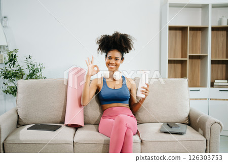 Active woman in athleisure sitting on yoga mat with tablet, headphones and modern home lifestyle. Active woman in athleisure sitting on yoga mat with tablet, headphones and modern home lifestyle. 126303753