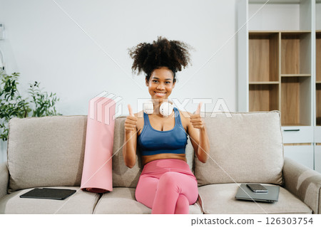 Active woman in athleisure sitting on yoga mat with tablet, headphones and modern home lifestyle. Active woman in athleisure sitting on yoga mat with tablet, headphones and modern home lifestyle. 126303754