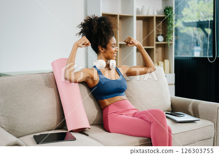 Active woman in athleisure sitting on yoga mat with tablet, headphones and modern home lifestyle. 126303755