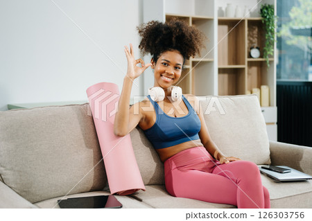 Active woman in athleisure sitting on yoga mat with tablet, headphones and modern home lifestyle. 126303756