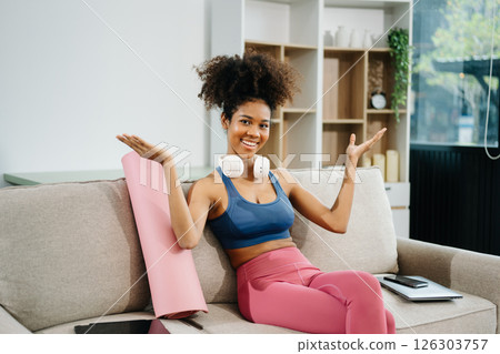 Active woman in athleisure sitting on yoga mat with tablet, headphones and modern home lifestyle. Active woman in athleisure sitting on yoga mat with tablet, headphones and modern home lifestyle. 126303757