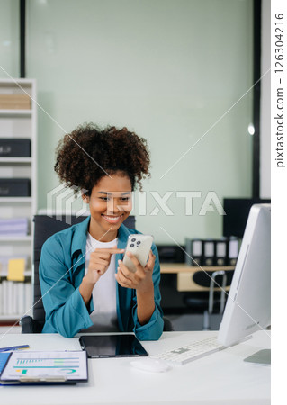 Young beautiful woman using laptop and tablet while sitting at her working place. 126304216
