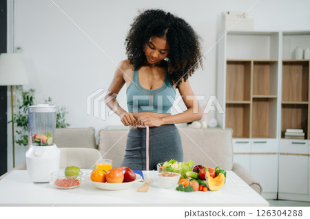 Smiling woman measuring waist, holding green apple with fruits, veggies, 126304288