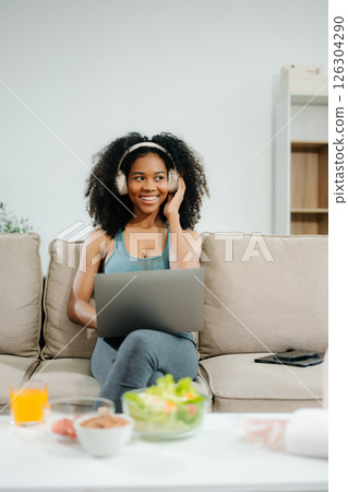A fit woman enjoys a fresh salad with fruits and juice, embodying wellness, nutrition, and vitality i 126304290