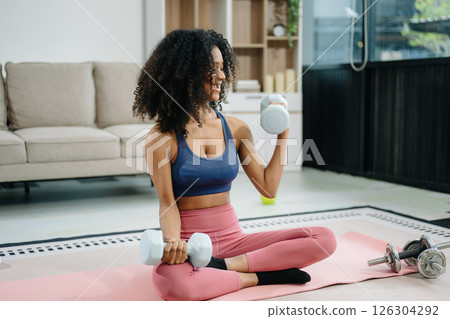 Woman Doing Yoga and Watching Online Tutorials on Laptop, Training in Living Room at home Woman Doing Yoga and Watching Online Tutorials on Laptop, Training in Living Room at home 126304292