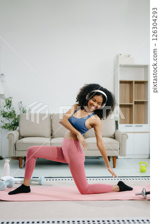 A young woman practices yoga and stretching with a mat and gym props, showcasing wellness, motivation, A young woman practices yoga and stretching with a mat and gym props, showcasing wellness, motivation, 126304293