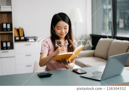 Female students note from the books at the Asian girl library sitting at the desk using laptop computer and tablet 126304332
