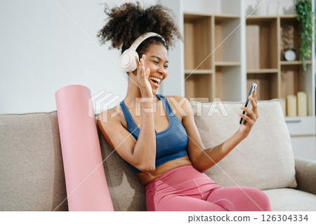 Active woman in athleisure sitting on yoga mat with tablet, headphones and modern home lifestyle. Active woman in athleisure sitting on yoga mat with tablet, headphones and modern home lifestyle. 126304334