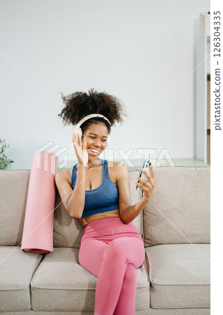 Active woman in athleisure sitting on yoga mat with tablet, headphones and modern home lifestyle. Active woman in athleisure sitting on yoga mat with tablet, headphones and modern home lifestyle. 126304335