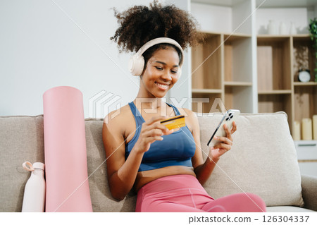 Active woman in athleisure sitting on yoga mat with tablet, headphones and modern home lifestyle. Active woman in athleisure sitting on yoga mat with tablet, headphones and modern home lifestyle. 126304337
