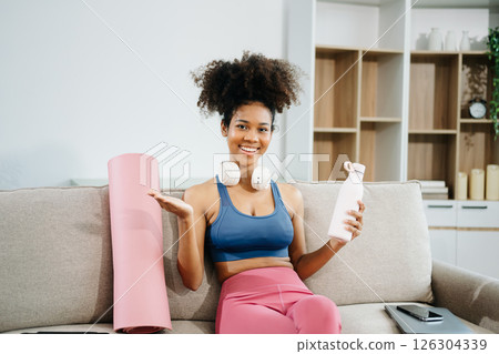 Active woman in athleisure sitting on yoga mat with tablet, headphones and modern home lifestyle. 126304339