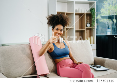 Active woman in athleisure sitting on yoga mat with tablet, headphones and modern home lifestyle. Active woman in athleisure sitting on yoga mat with tablet, headphones and modern home lifestyle. 126304340