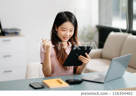 Asian woman sitting at a desk using a laptop computer Navigating Finance and Marketing with Technology 126304462
