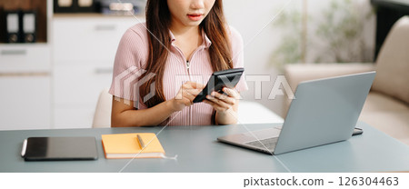 Asian woman sitting at a desk using a laptop computer Navigating Finance and Marketing with Technology 126304463