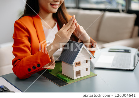 Female real estate agent is use hands to protect red roof for the concept of real estate investment about house trading, purchase 126304641
