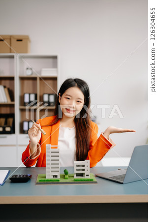 Real estate broker agent presenting and consult to customer to decision making sign insurance form agreement, home model, concerning mortgage loan offer Real estate broker agent presenting and consult to customer to decision making sign insurance form agreement, home model, concerning mortgage loan offer 126304655