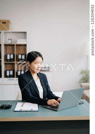Businesswoman Analyzing Finance on Tablet and Laptop at modern Office Desk tax, report, accounting, statistics, and analytical research concept 126304692