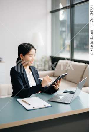 Businesswoman Analyzing Finance on Tablet and Laptop at modern Office Desk tax, report, accounting, statistics, and analytical research concept Businesswoman Analyzing Finance on Tablet and Laptop at modern Office Desk tax, report, accounting, statistics, and analytical research concept 126304725