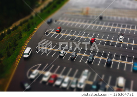 Overhead shot of a parking lot with some vehicles. An aerial view captures an empty parking lot with cars placed, highlighting the available space. 126304751