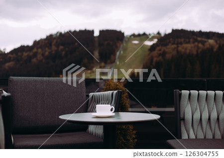 A cup of coffee, tea on a table and scenic mountain view. A tranquil scene of hotel terrace, rooftop with mountain backdrop. Relaxation, leisure scene A cup of coffee, tea on a table and scenic mountain view. A tranquil scene of hotel terrace, rooftop with mountain backdrop. Relaxation, leisure scene 126304755