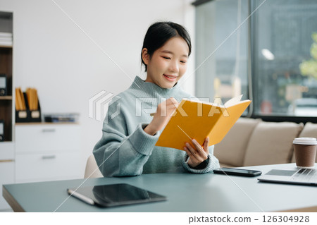 Young smiling woman wearing headphones and talking into a microphone at the radio station, entertainment a live podcast for their channel, communication 126304928