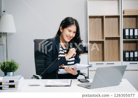 Asian businesswoman working in the office with working notepad, tablet and laptop documents Asian businesswoman working in the office with working notepad, tablet and laptop documents 126305077
