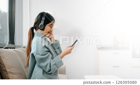 Asian woman using the smartphone and tablet on the sofa at home office Asian woman using the smartphone and tablet on the sofa at home office 126305080