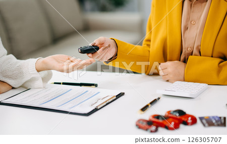 Asian people car salesman or sales manager offers to sell a car and explains of signing a car contract and signing car insurance document 126305707