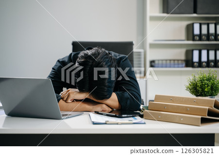 Frustrated young businessman working on a laptop computer sitting at his working place 126305821