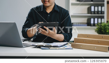 Confident businessman working on laptop, tablet and smartphone at her workplace 126305870