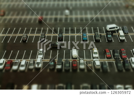A top-down shot reveals a well-organized huge parking lot filled with various cars. An aerial view showcases various vehicles on urban city parking. 126305972