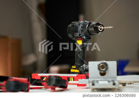 Electric cordless drill with bits and hand tools on workbench in workshop. Home renovation, construction and repair concept 126306080