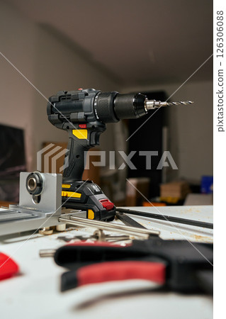 Electric cordless drill with bits and hand tools on workbench in workshop. Home renovation, construction and repair concept 126306088